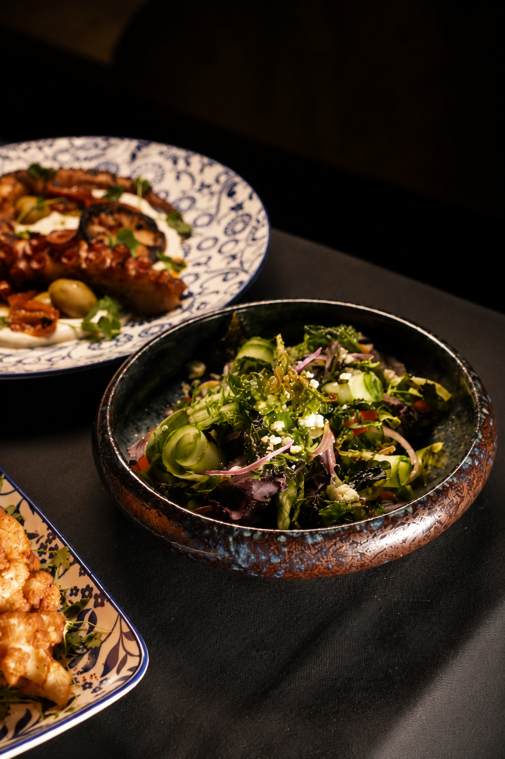 Shaved cucumber and herb salad in a dark glazed bowl
